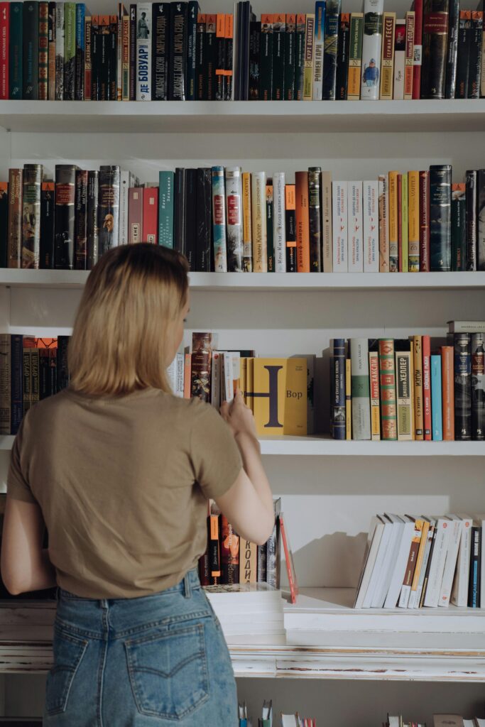 pexels photo 4865738 4865738 A young woman browses a library bookshelf, exploring various literature titles.